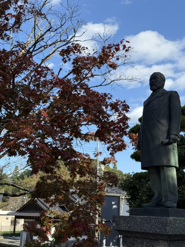 トップ画像。伊藤博文の銅像（立像）とモミジの紅葉の写真。