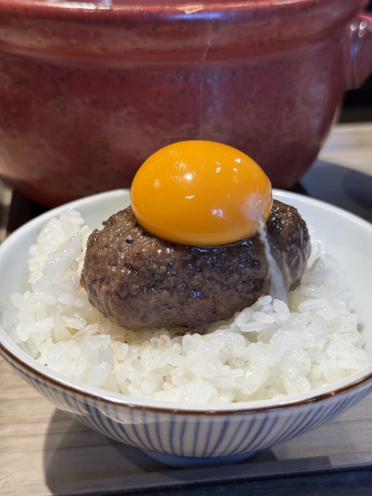 『炭焼食堂 JYUJYUTEI』ハンバーグに卵をのせてご飯の上にのせた写真。