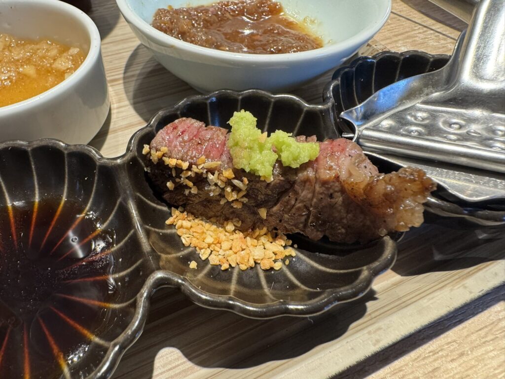 『炭焼食堂 JYUJYUTEI』切り落としステーキ定食の焼いたお肉に薬味をのせた写真。